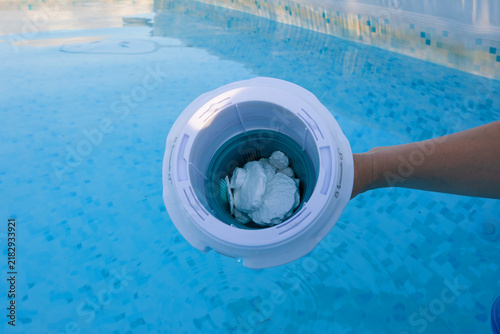 Foto Hand holding a floating dispenser filled with chlorine tablets, treating and san