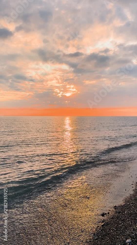 Calm waves at sunset. Wave splashing over pebbles at sea with foam. Rolling ocean waves. Summer paradise beach background at sunset