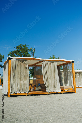 Cuadro en lienzo Beach shelter with curtains and wooden structure under clear blue sky at a sandy
