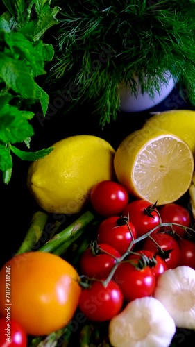 Healthy vegetarian vegetable platter with asparagus tomatoes cucumbers garlic cabbage and lemon on black plate close up