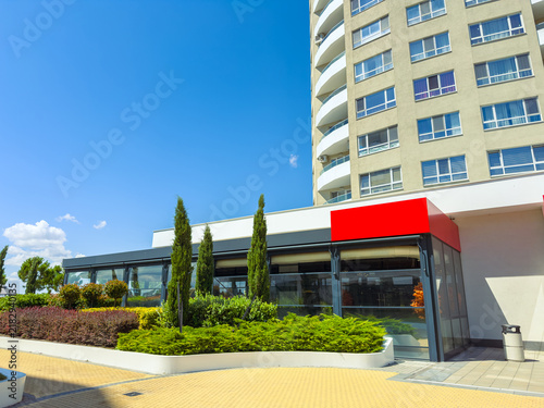 Foto Bright day at a restaurant near a tall building with green plants and clear sky