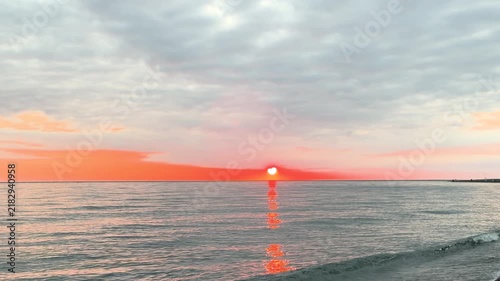 Calm waves at sunset. Wave splashing over pebbles at sea with foam. Rolling ocean waves. Summer paradise beach background at sunset