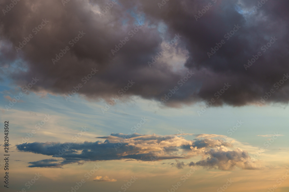 Obraz premium Beautiful sunset clouds in blue sky background, fluffy cumulus cloudscape illuminated by warm sun rays at golden hour evening, gentle peace and hope atmosphere conceptual scenic nature wallpaper. 