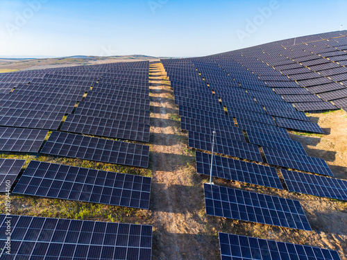 Konstfotografi Large solar farm with numerous solar panels located in an open field under brigh