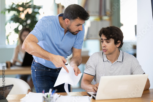 Strict boss reprehending office worker because of mistake on computer during workday