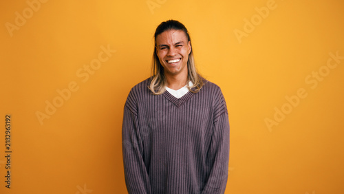 Canvastavla Young Latino man with long hair smiling broadly, expressing happiness and cheerf