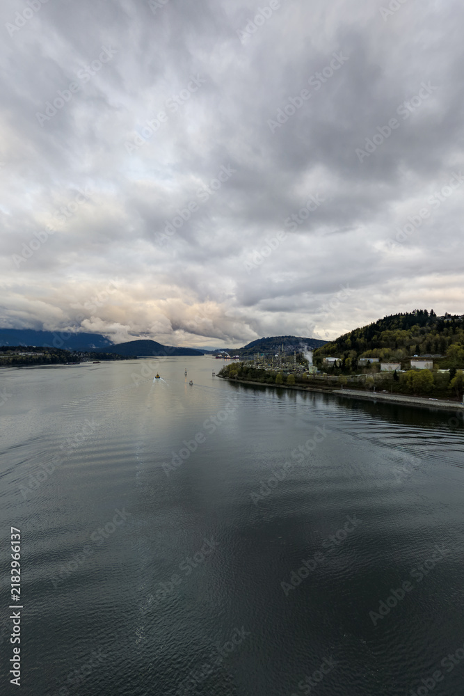 Fototapeta premium Overcast River Landscape With Small Boat and Industrial Shoreline Near Vancouver, BC, Canada