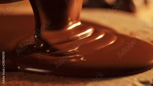 Liquid chocolate pouring onto a wooden surface in a close up macro shot.