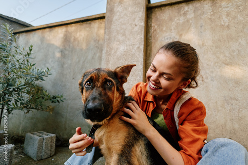 Canvas Print Happy teenage girl hugging her german shepherd dog in a rustic backyard, smiling with joy, showing friendship, love and bonding between child and pet outdoors