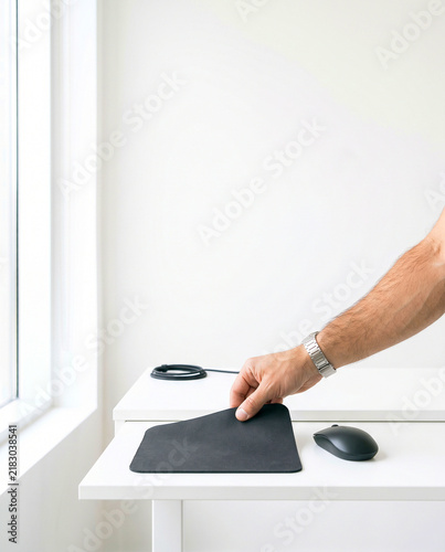 Hand Placing Black Mousepad next to Wireless Mouse on White Desk
