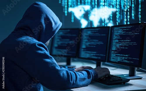 Obraz na płótnie Hacker in a hoodie coding on digital monitors to commit cybercrime with computer network data and internet security