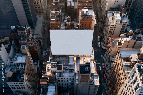 Top down drone view of a blank white billboard on a rooftop among city blocks