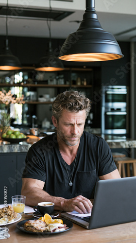 Man working on laptop in a cafe with food on table