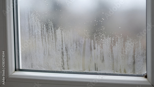 Steamed up Window: A close-up shot reveals the condensation on a windowpane, with water droplets and streaks obscuring the view of the outdoors, suggesting a cold day or poor insulation.
