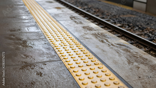 Tactile Paving at Train Station: Close-up of yellow tactile paving on a train station platform, indicating the edge and providing guidance for visually impaired individuals.