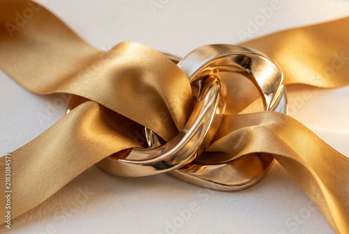 Gold Silk Ribbons Intertwined With Reflective Metallic Shapes On White Surface Warm Golden Hour Lighting Luxury Texture