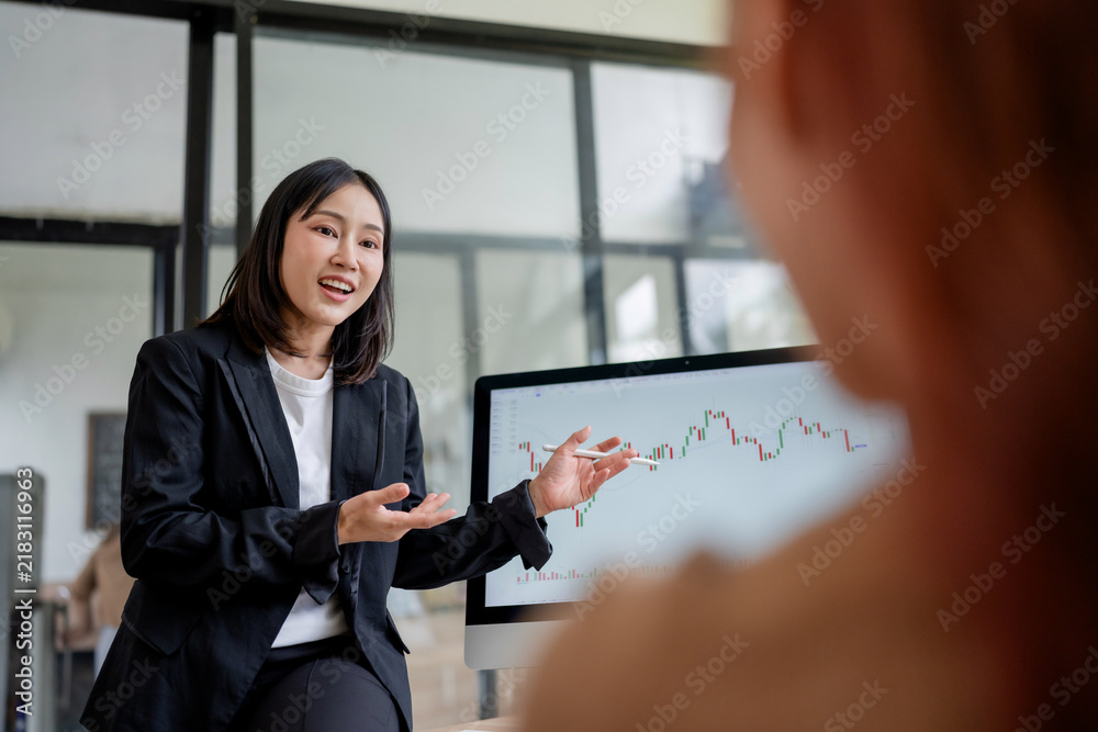 Obraz premium Businesswoman presenting financial market analysis on a computer screen to a colleague, discussing investment strategies and growth