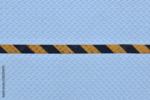 yellow black stripes hazard warning tape on light blue metal diamond plate