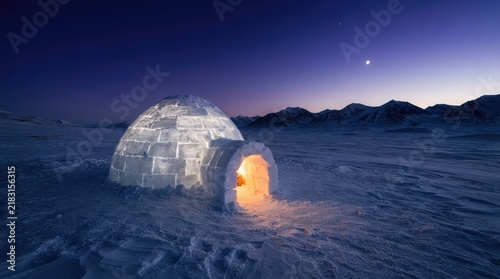 A glowing ice igloo illuminated from within set against a serene arctic landscape under a deep blue twilight sky with distant snow capped mountains