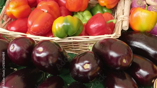 Fresh eggplants and colorful bell peppers selling at a market stall in Paris