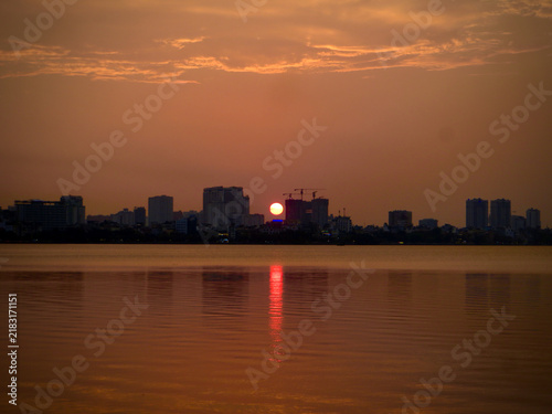 Distant Urban Sunset Reflected Across Tranquil Waterfront on West Lake in Hanoi, Vietnam