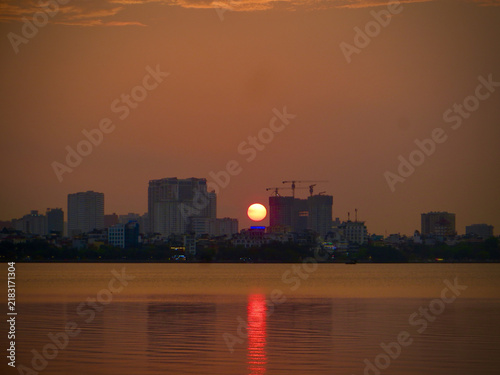 Vivid Sunset Reflection on Water Beneath a Modern City Skyline on West Lake in Hanoi, Vietnam