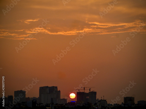 Fiery Orange Sunset Above Silhouetted City Skyline and Cranes on West Lake in Hanoi, Vietnam