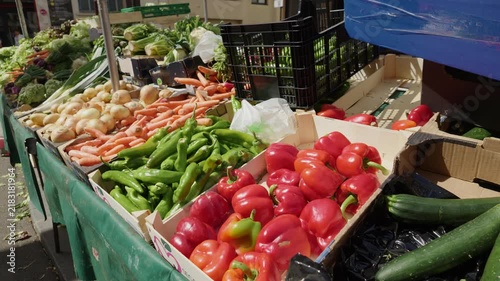 Fresh vegetables like peppers, carrots, and onions displayed for sale at a vibrant outdoor market