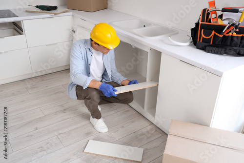 Male worker assembling counter with shelf in kitchen