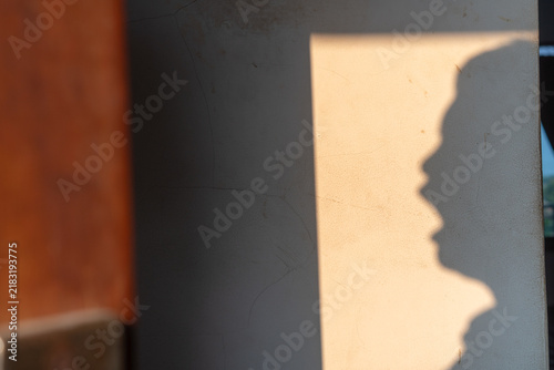 Foto Silhouette shadow of an unrecognizable person with open mouth screaming on a sunlit wall