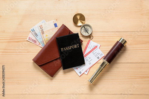 Composition with passport, money, tickets, spyglass and compass on wooden bac...