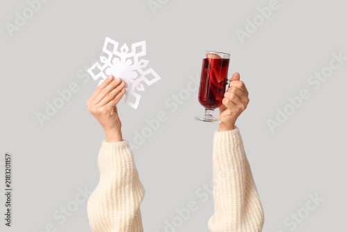 Fotografía Female hands with glass of tasty mulled wine and paper snowflake on white backgr