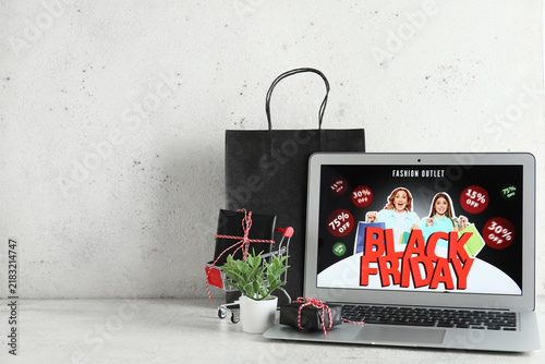 Laptop with Black Friday sale advertisement and gift boxes on white table