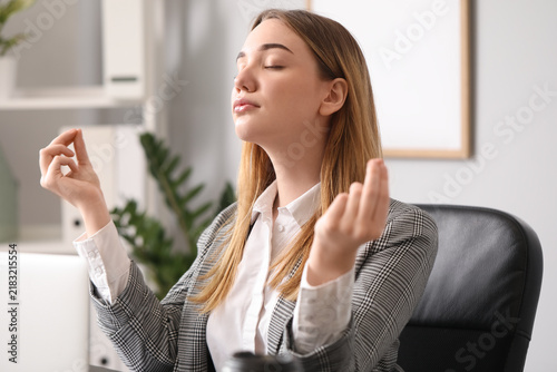 Young businesswoman meditating at table in office. Balance concept