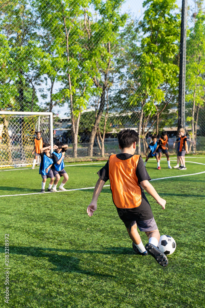 Obraz premium Young school children dribbling football on outdoor soccer field. 