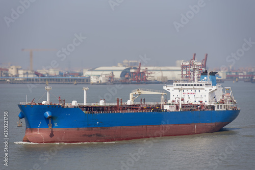 Quadro su tela Tanker ship underway on the Yangtze River, moving through an industrialized section of the waterway with factories, terminals and port infrastructure visible along the riverbanks