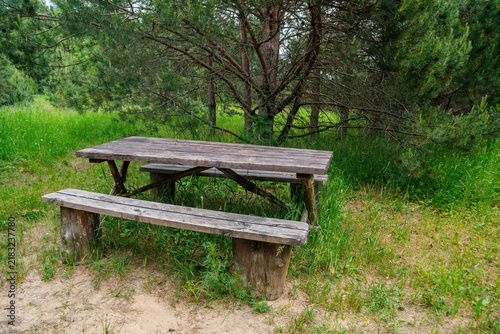 An empty wooden table with a bench for summer picnics in the countryside. An empty resting place during hikes.