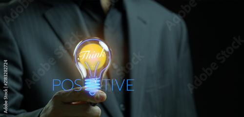 фотографія Businessman hand holding glowing incandescent lightbulb with positive text HUD