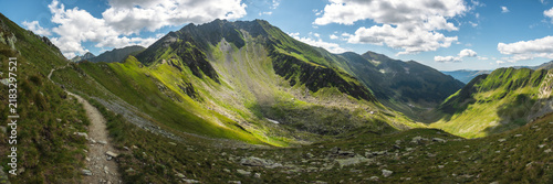Foto Beautiful green mountain valley with rocky scree slopes under sunny sky