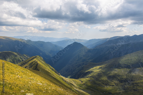 Quadro su tela Deep mountain valley enclosed by steep ridges under blue sky