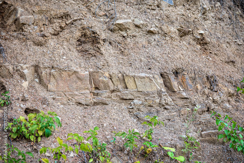 Cuadro en lienzo Exposed sandstone, loose stones and sandy soil in a terraced slope cut, revealing natural rock layers, weathering and geological structure after earthworks