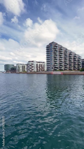 Navigating along the waterfront of Islands Brygge district, with its modern architecture, in Copenhagen, Denmark under a partially cloudy blue sky during the day - stock video