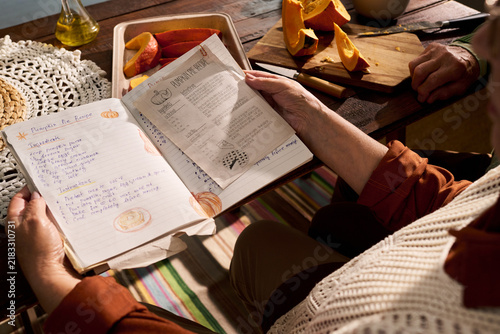 Fotografía Senior Caucasian woman reading handwritten pumpkin pie recipe book while preparing autumn meal