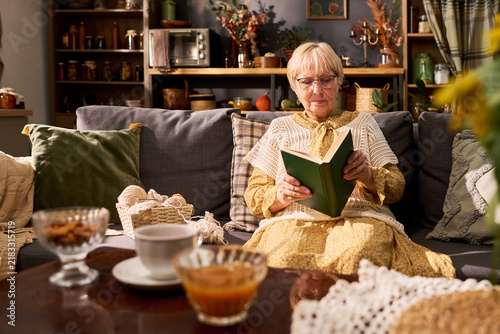 Canvastavla Senior Caucasian woman wearing eyeglasses reading book at home