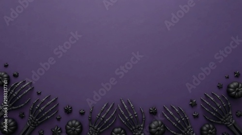 Halloween flat lay with skeleton hands and black pumpkins on a dark purple background