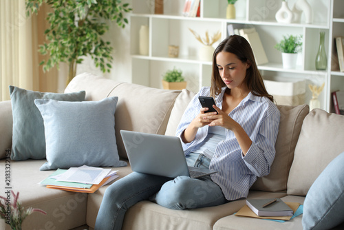 Telecommuter checking phone woriking at home