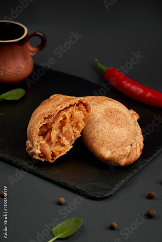 Fotografie Halved savory baked pie with braised cabbage filling on slate board