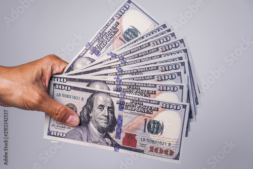 фотографія A wad of US$100 bills is being held by someone.