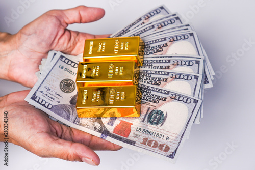 Konstfotografi A person's hand holding a stack of US$100 bills and three gold bars