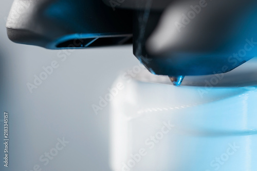 Extreme macro shot of 3D printer nozzle printing white plastic object